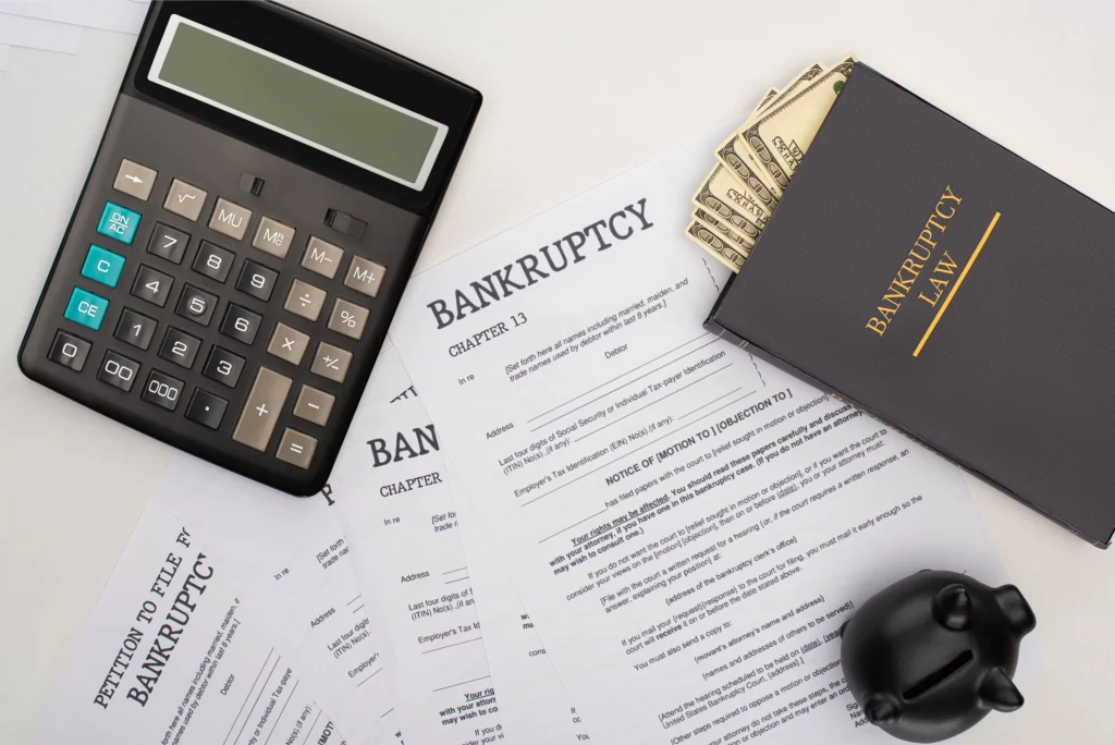 Ilustration pour secteur des finances. l'image montre une calculatrice, des documents de declaration de faillite ainsi qu 'un carnet avec 'Bankruptcy Law' ecrit sur la face principale